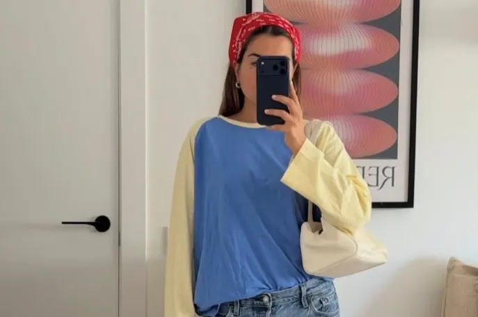 Look com camiseta raglan azul de mangas amarelas, jeans reto, bolsa off-white e bandana vermelha